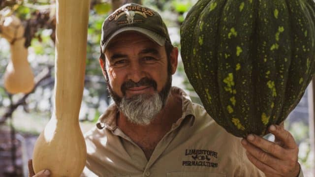One Acre Permaculture Farmer Brett Cooper holding Gourds